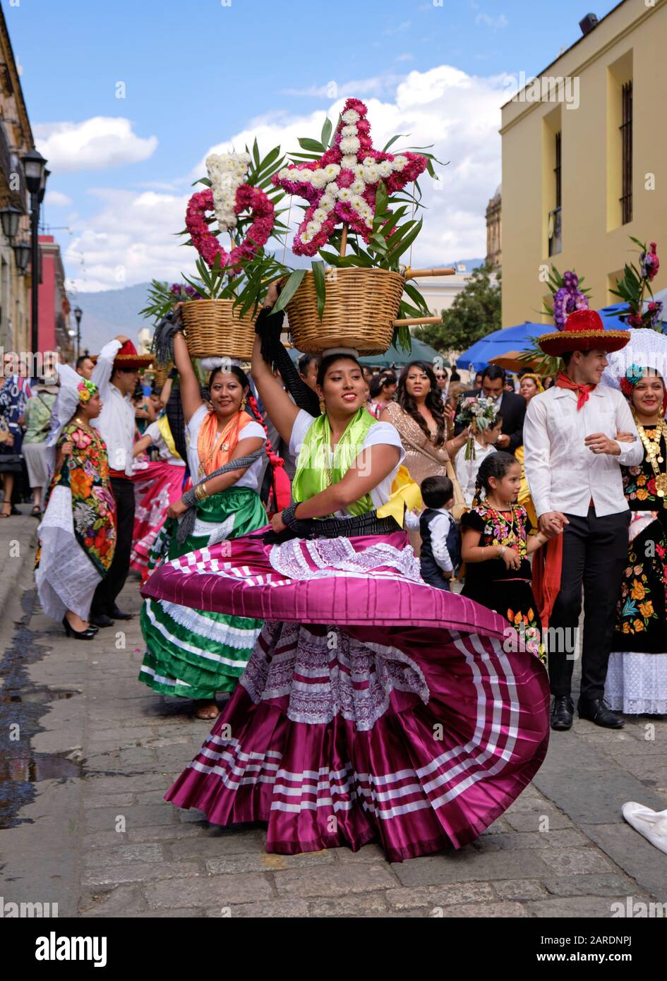 Frau tanzt in fließenden traditionellen Outfit mit Blumenkorb Teil der traditionellen Parade (Calenda de Bodas) auf den Straßen von Oaxaca. Stockfoto
