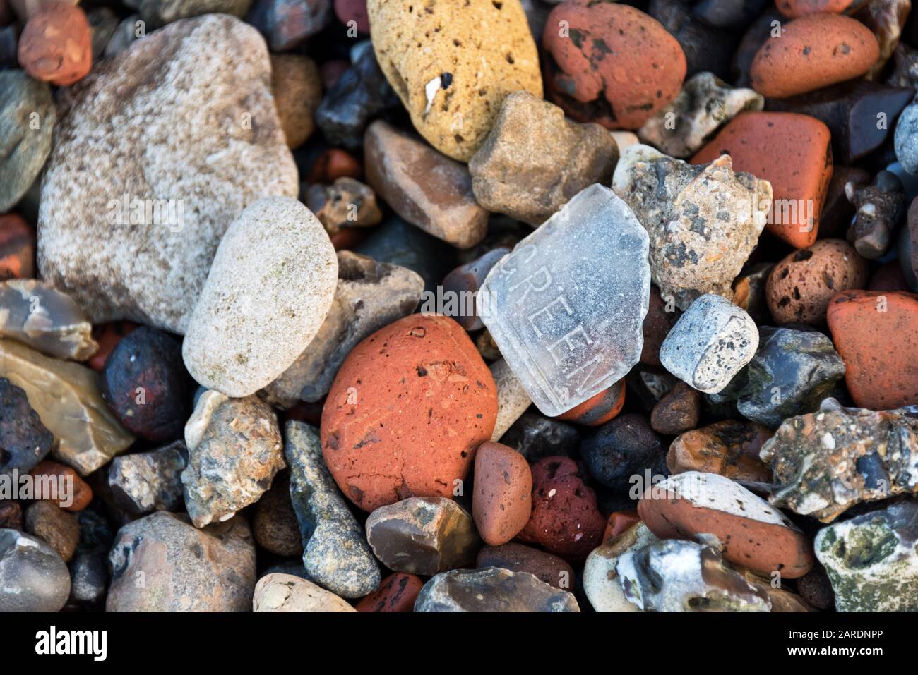 Meeresglas mit dem eingeprägten Wort "grün" zwischen roten und gelben Ziegelsteinen, Kreide und Feuersteinen auf dem Greenwich Vorwerk, London. Stockfoto