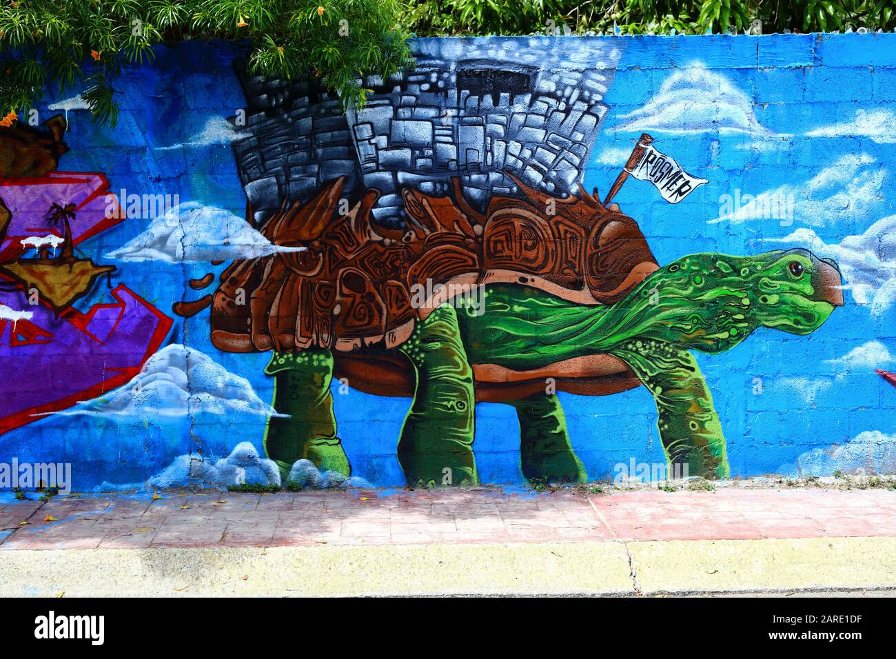 Bunt bemalte Graffiti-Grafiken im indigenen und Maya-Stil zeigen eine Schildkröte mit Ruinen, die auf dem Rücken an einer Cinderblockwand in Bacalar, Mexiko aufragt. Stockfoto