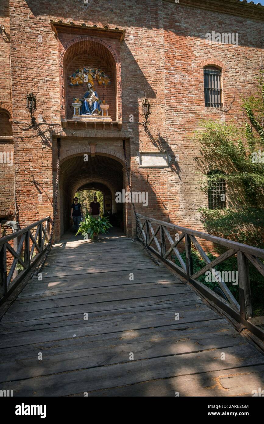 Asciano, Italien - Touristen gehen in Richtung der hölzernen Zugbrücke, die aus dem Kloster Oliveto, Abtei Monte Oliveto Maggiore, führt Stockfoto