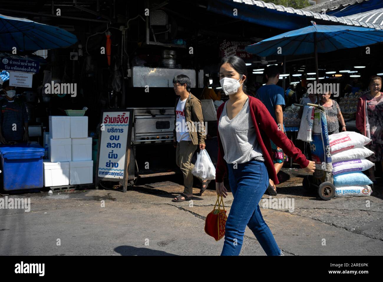Frauengesichtsmaske; Tragen einer Gesichtsmaske gegen Umweltverschmutzung auf einem asiatischen Straßenmarkt. Thailand S. E. Asien Stockfoto