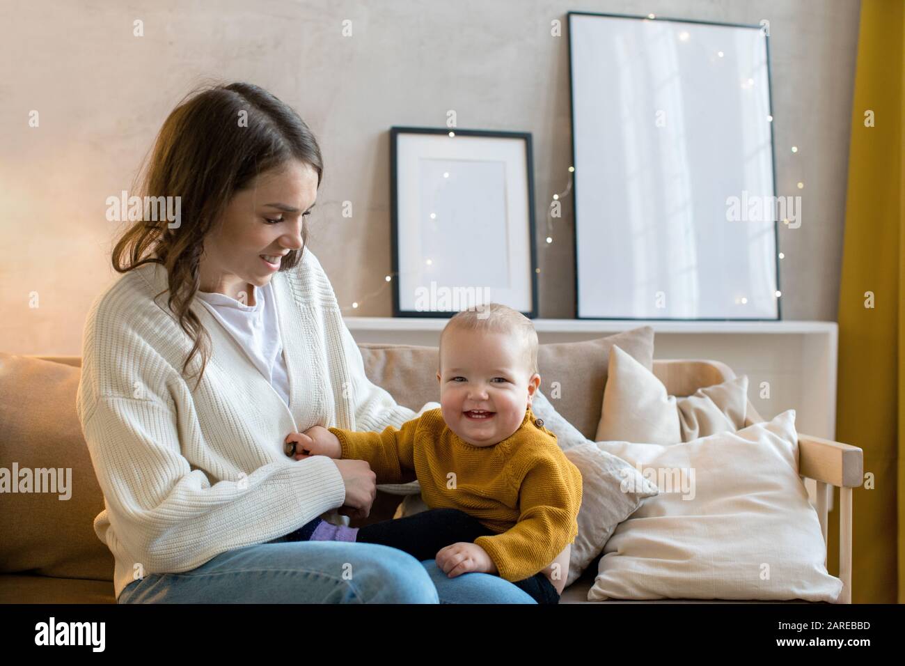 Zufriedene Mutter mit Kleinkind auf Sofa Stockfoto