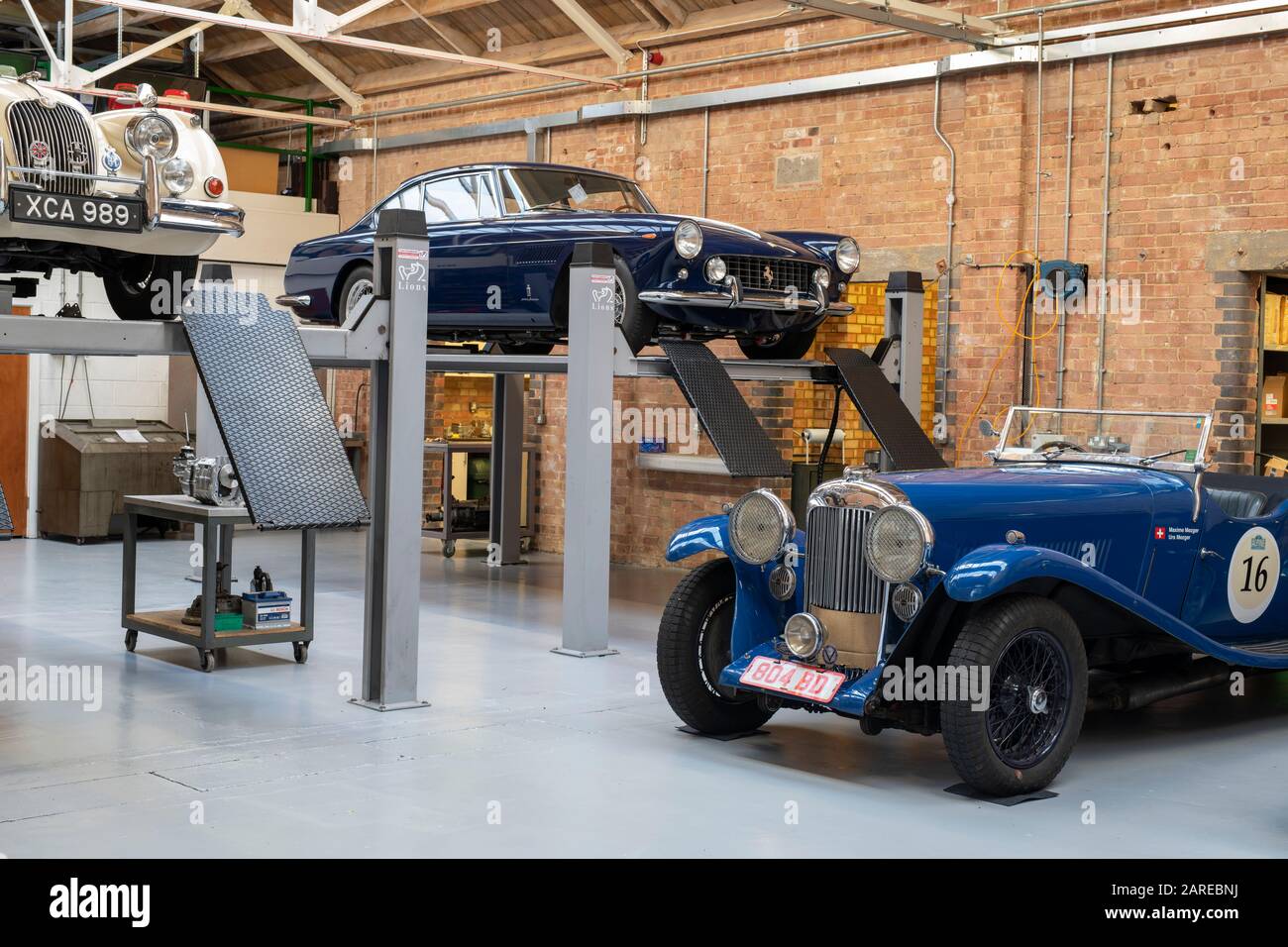 Lagonda und Ferrari Oldtimer in einem Workshop im Bicester Heritage Centre Sundat Scramble Event. Bicester, Oxfordshire, England Stockfoto