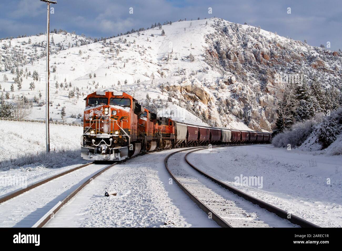 Ein BNSF train Kommen hinunter die Spuren im Schnee An einem kalten, hellen, sonnigen Tag. Bei Bearmouth, westlich von Drummond, Montana in Granit County. Stockfoto
