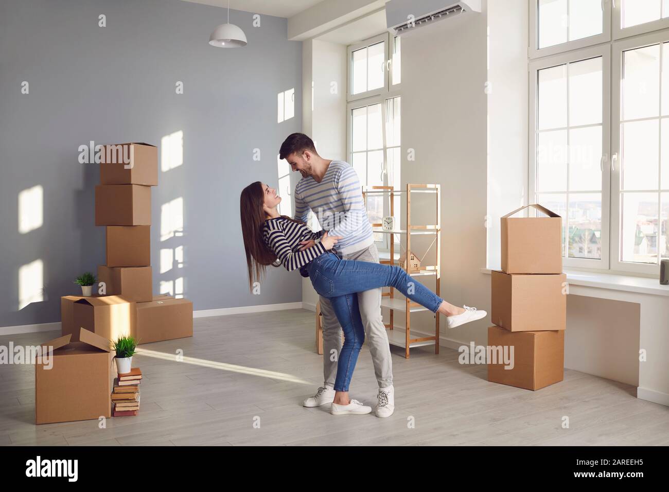Ein fröhliches Paar spielt mit einem beweglichen Kasten in einem hellen Raum eines neuen Hauses. Stockfoto