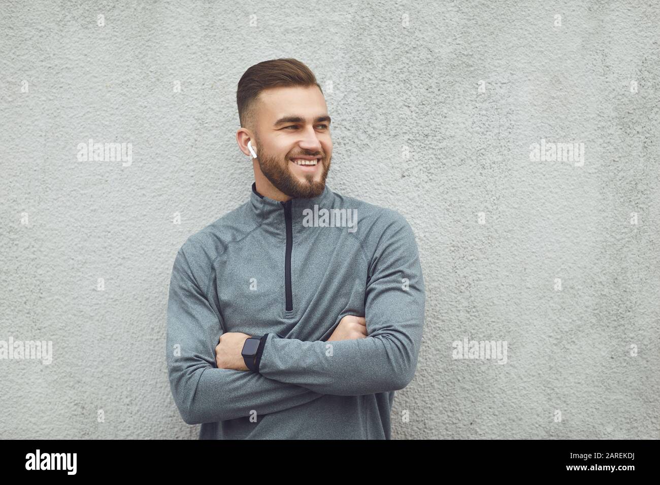 Bärtiger Kerl in Sportkleidung auf grauem Hintergrund. Stockfoto