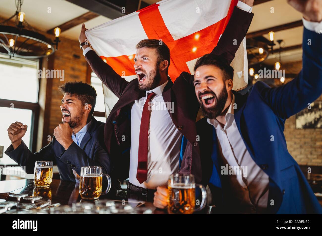 Männerfans schreien und beobachten Fußball im Fernsehen und trinken Bier in einer Kneipe Stockfoto