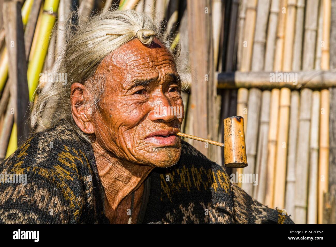 Porträt eines alten Apatani-Mannes, der die traditionelle Frisur mit dem Knop an der Stirn trägt, rauchende Pfeife Stockfoto