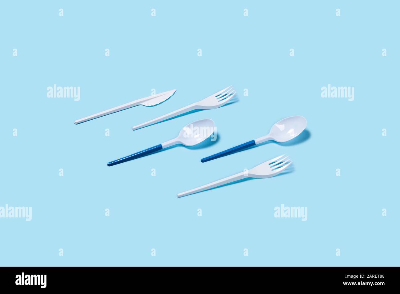 Abbildung der weißen Kunststofflöffel auf blauem Hintergrund. Flache Lage, Draufsicht. Flaches Layout, Draufsicht, Kopierbereich. Stockfoto