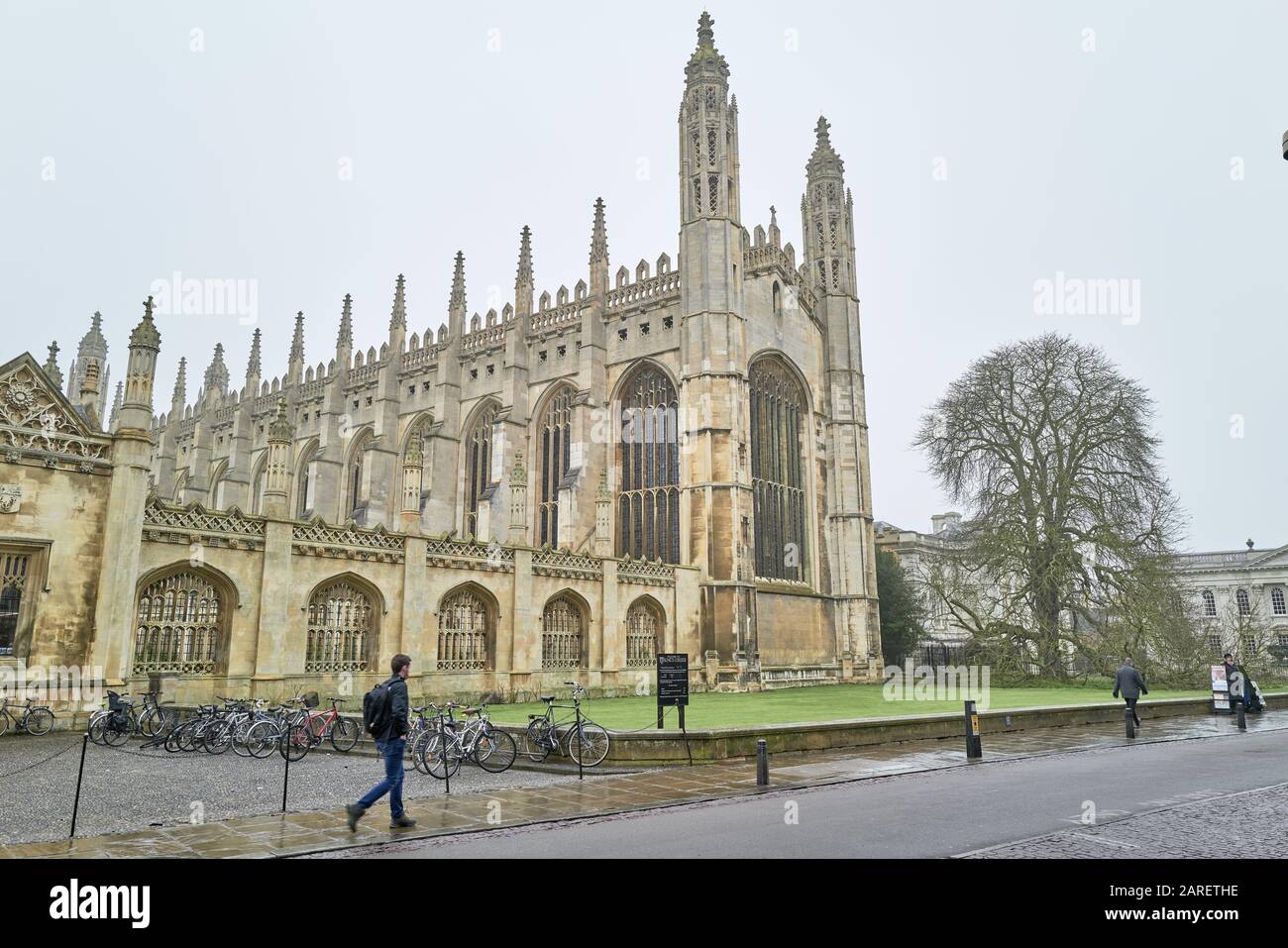 Ein Student geht an einem nassen Wintertag an der mittelalterlichen Kapelle am King's College der Universität Cambridge in England vorbei. Stockfoto