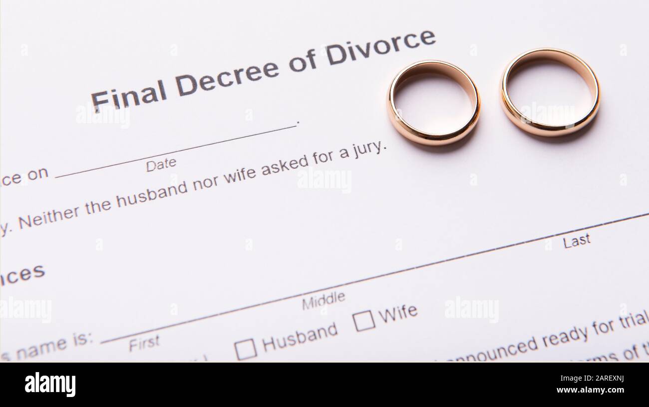 Zwei goldene Trauringe auf dem endgültigen Scheidungsdekret Stockfoto