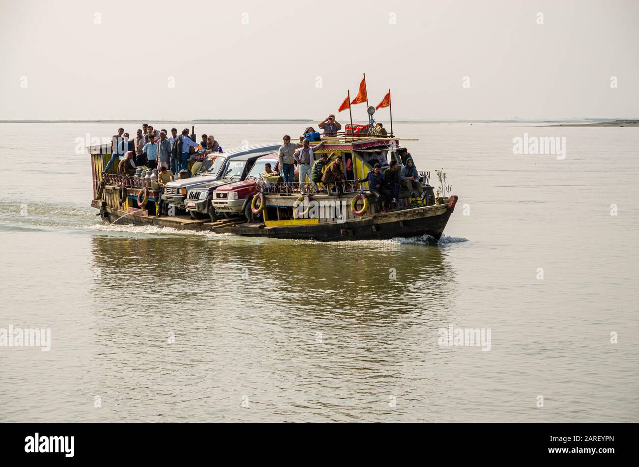 Überlastetes Fährschiff mit 3 Jeeps und vielen Menschen, die den Fluss Brahmaputra überqueren Stockfoto