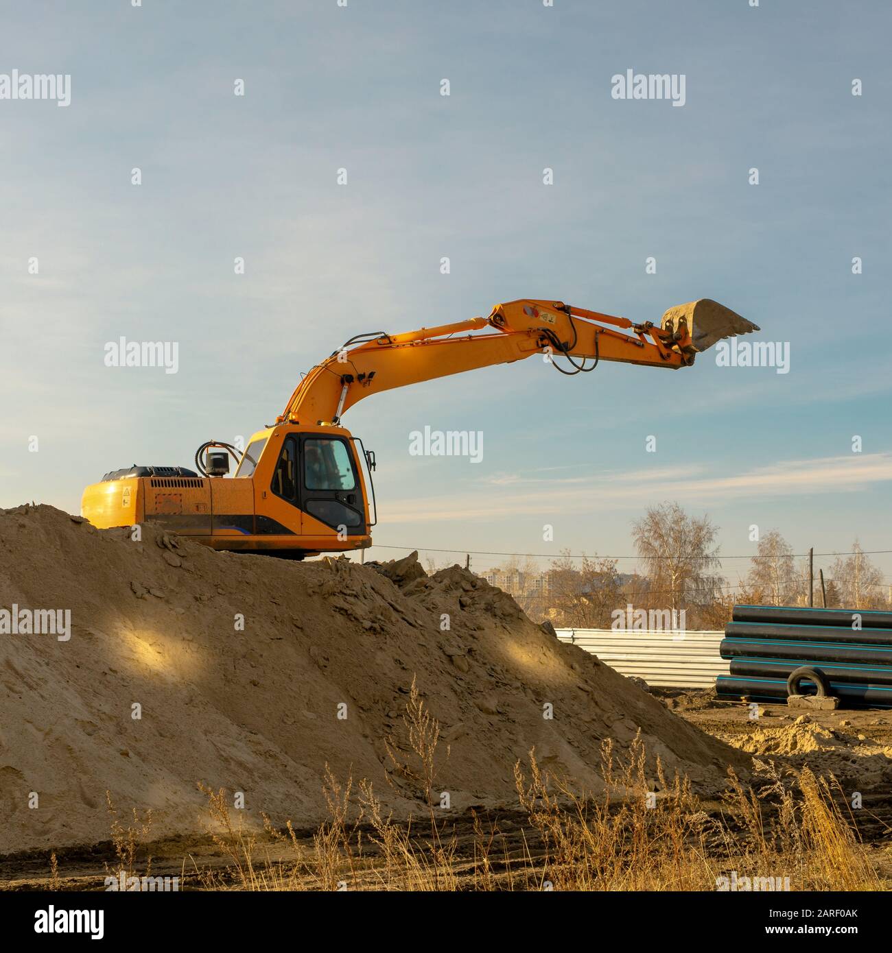 Gelbe Baggermaschine bei Erdbewegungsarbeiten an der Baustelle. Verlegung der Hauptnetze von Haus-, Industrie- und Sturmwasser. Stockfoto