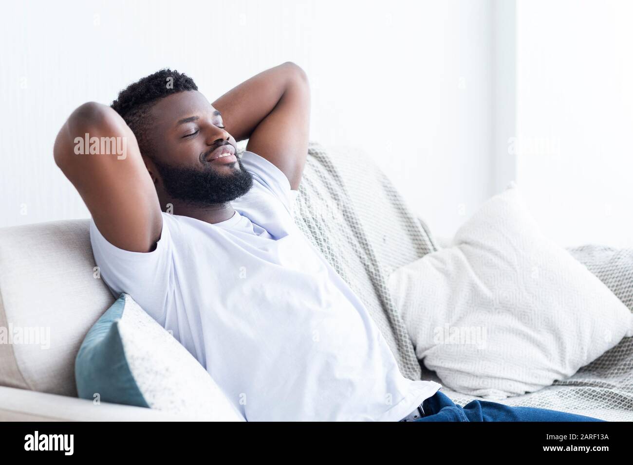 Entspannter afroamerikanischer Mann, der zu Hause auf dem Sofa ruht Stockfoto