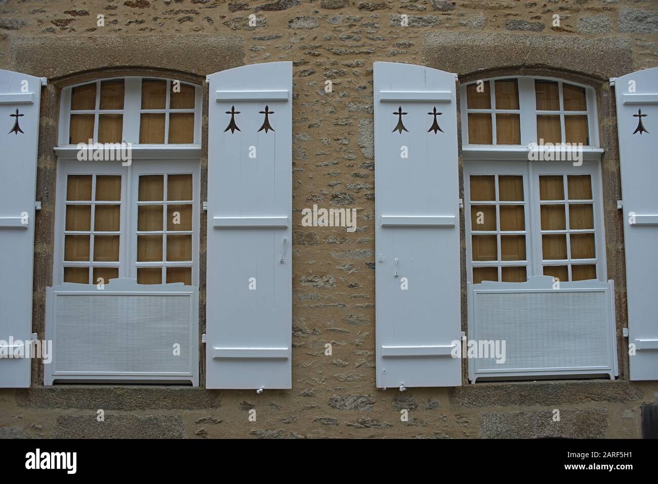 Zwei Fenster mit Jalousien im alten Stil an der Steinwand Stockfoto