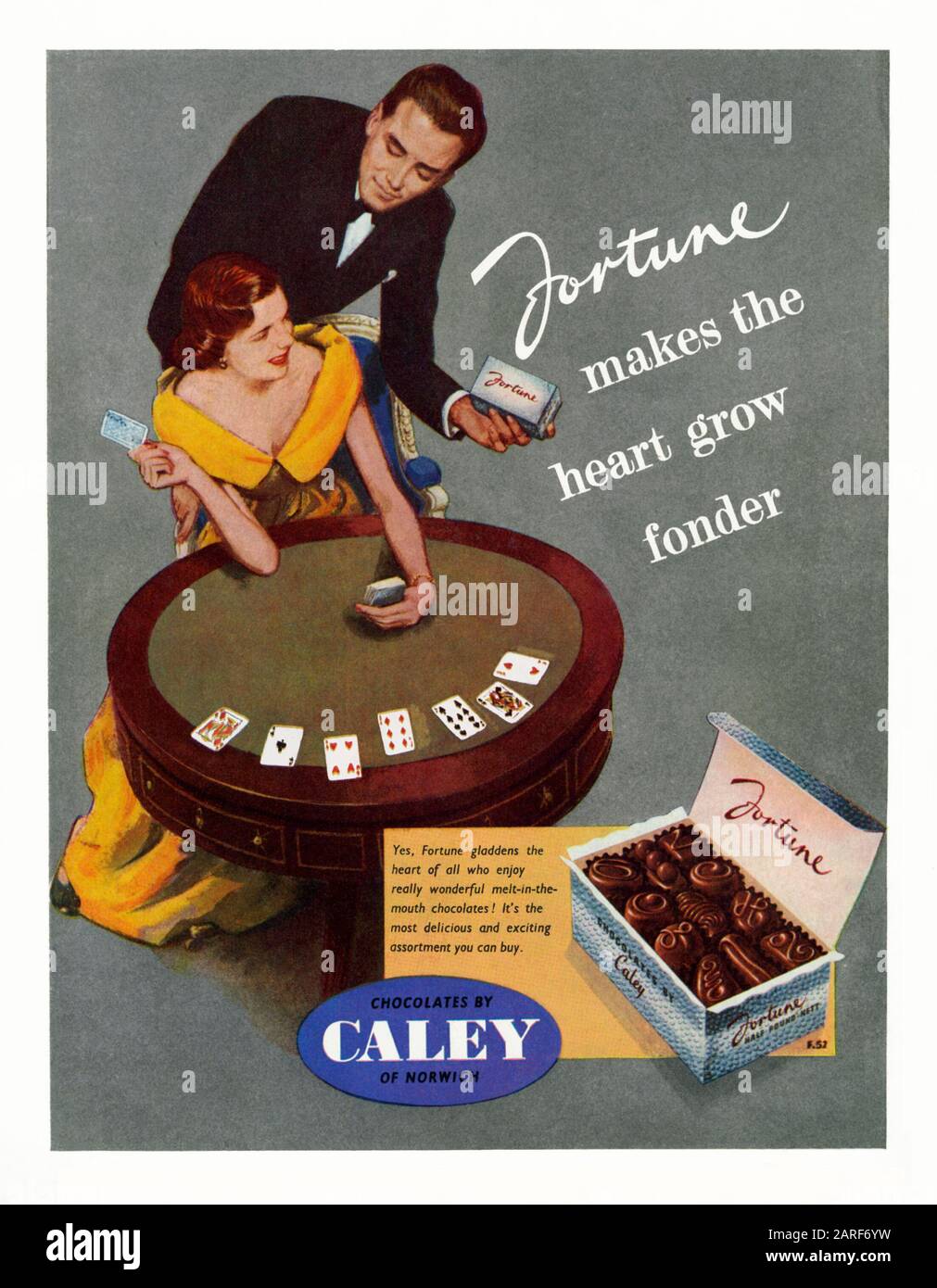 Werbung für Caley's Chocolates, 1951. Dies erschien im offiziellen Leitbuch für das Festival of Britain Pleasure Gardens, Battersea Park, London, 1951. Die Abbildung zeigt ein ausgeklügeltes Paar, das Karten spielt, und eine Schachtel "Fortune"-Schokolade. Albert Caley begann das Unternehmen im Jahr 1863 in Norwich, Norfolk, England, Großbritannien. Kakao- und Schokoladenprodukte erschienen in den 1880er Jahren. 1929 kaufte Unilever Caley's. Mackiebhels kaufte 1932 die Schokoladenfirma von Unilever. 1969 verschmolz sie mit Rowntree's zur Süßwarenfabrik Rowntree Mackintosh, die 1988 von Nestlé selbst übernommen wurde. Stockfoto