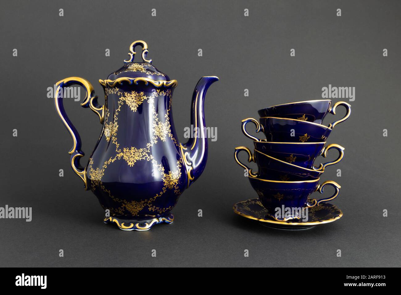 Nahaufnahme eines schönen kobaltblau gefärbten Vintage-Porzellan-Teesets  mit goldenem Blumenmuster auf dunkelgrauem Hintergrund. Das Set umfasst  einen Teekopf, einen Stockfotografie - Alamy