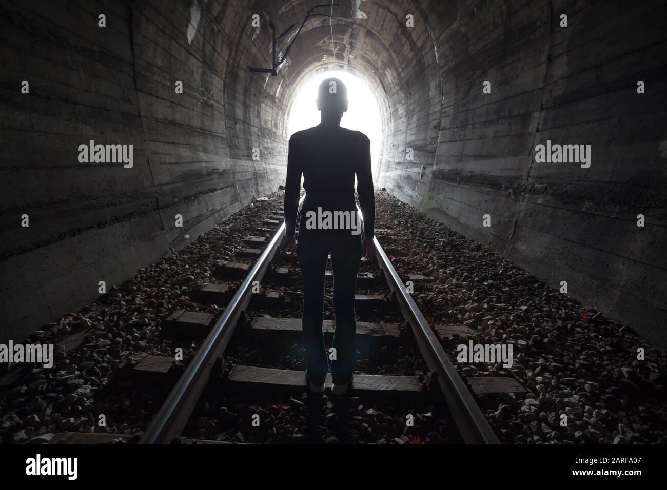 Abfahrt von Darknes - Licht am Ende des Tunnels, Männer im Eisenbahntunnel. Stockfoto
