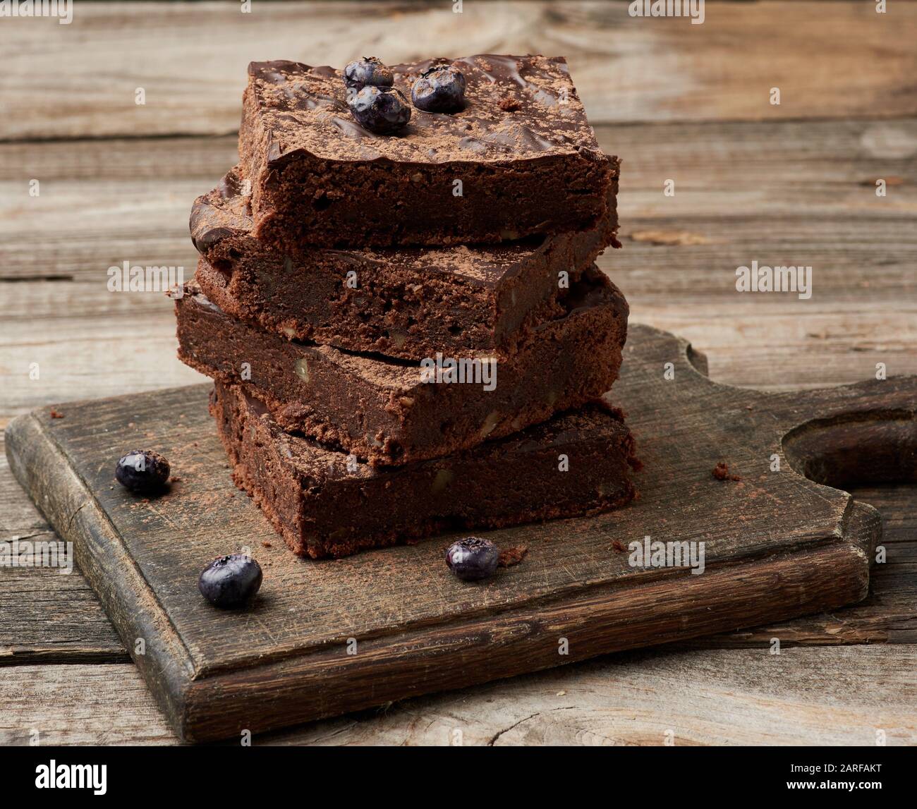 Stapel von Square gebackene Scheiben von Schokoladenkuchen Schokoladenkuchen mit Walnüssen auf einer hölzernen Oberfläche. Zubereitet hausgemachte Speisen. Gebäck Schokolade. Süße Speisen, Hausgemachte Stockfoto