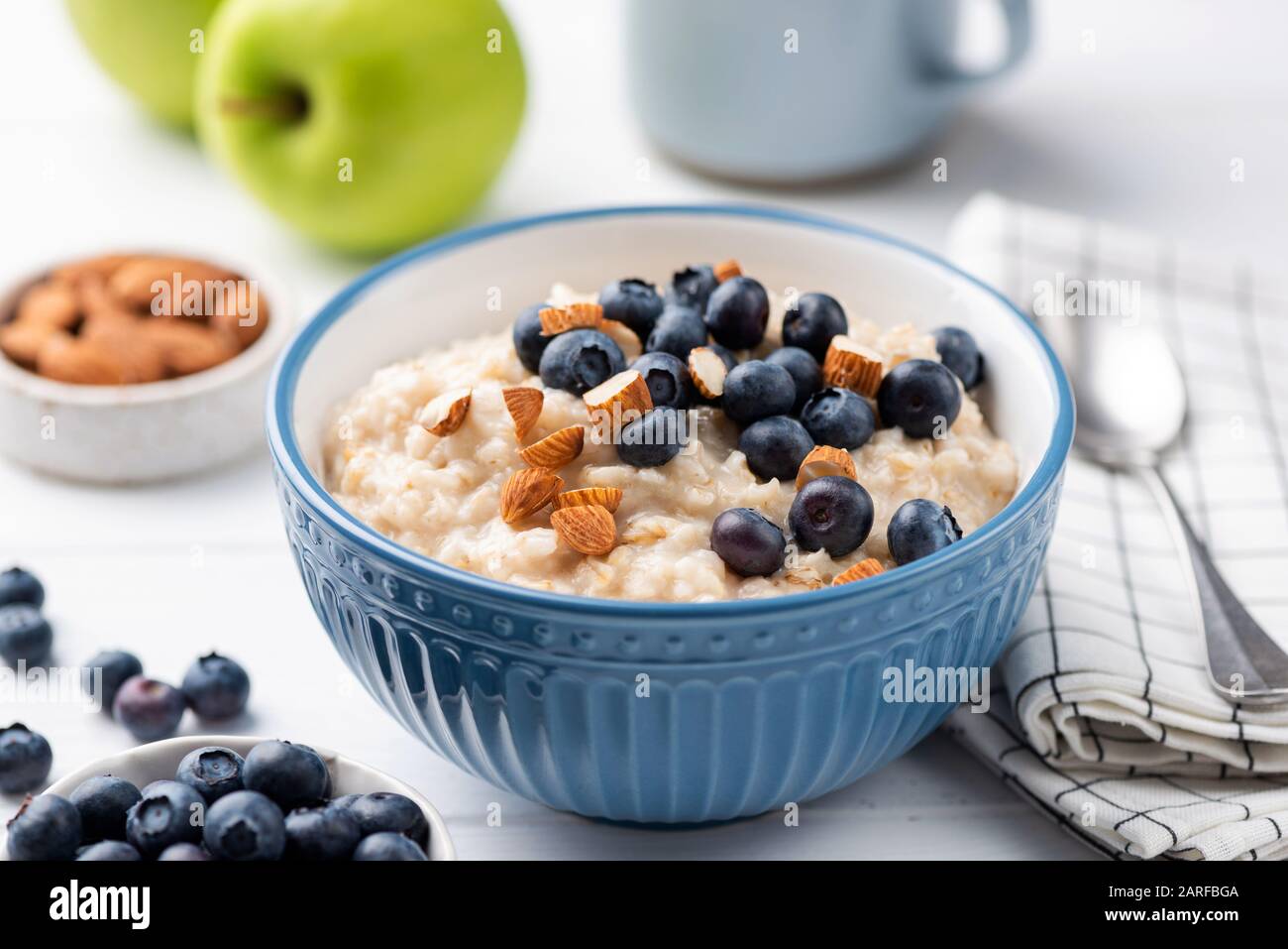 Haferbrei Porridge Schüssel mit Blaubeeren und Mandeln in blauer Schüssel. Gesundes Frühstück, vegetarisches Frühstück mit Ballaststoffen und langsamen Karben Stockfoto
