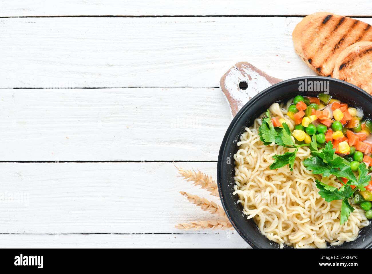 Asiatische Suppe mit Nudeln und Gemüse in einer Schüssel, mit Toastbrot. Diätetische Speisen. Draufsicht. Freier Speicherplatz. Stockfoto