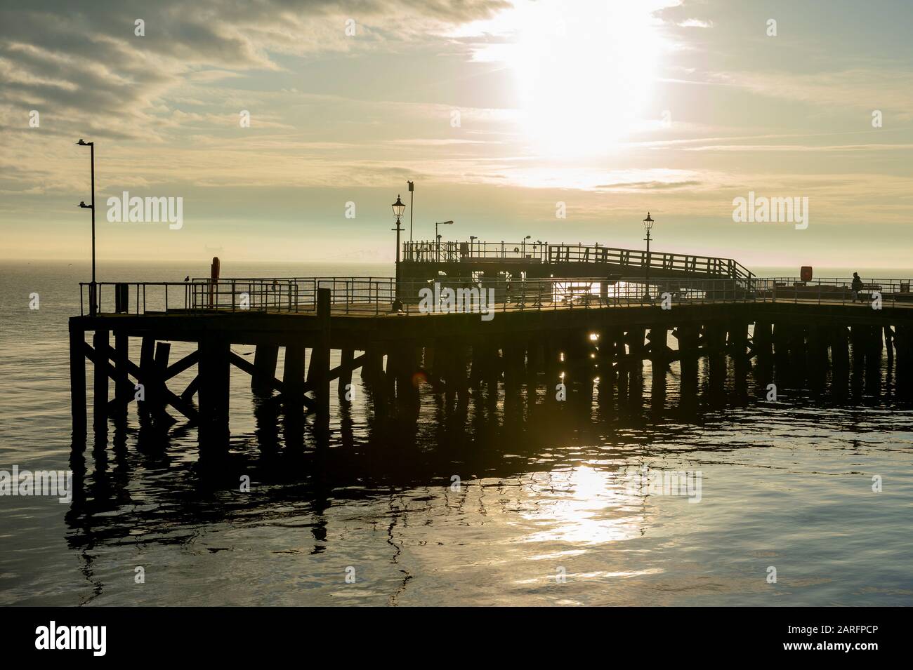 Gezeigt wird Victoria Pier in Kingston Upon Hull, der gegen eine untergehende Sonne fast in Silhouette steht. Stockfoto