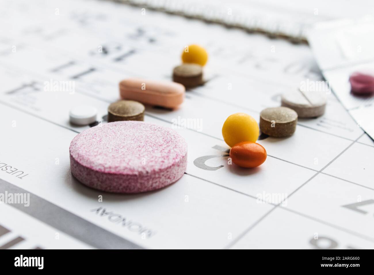 Pillen, Ergänzungen und Medikamente für die Krankheit. Ein Haufen verschiedener Pillen auf einem Kalenderhintergrund. Gesundheitswesen Stockfoto
