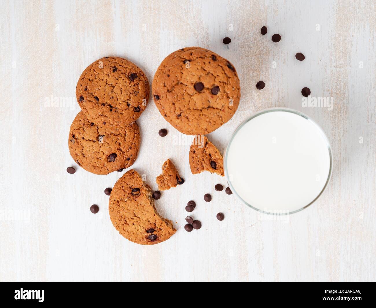 Haferflocken mit Schokoladentropfen und Milch aus Glas, gesunder Snack. Heller Hintergrund, weißer Holztisch, Draufsicht Stockfoto