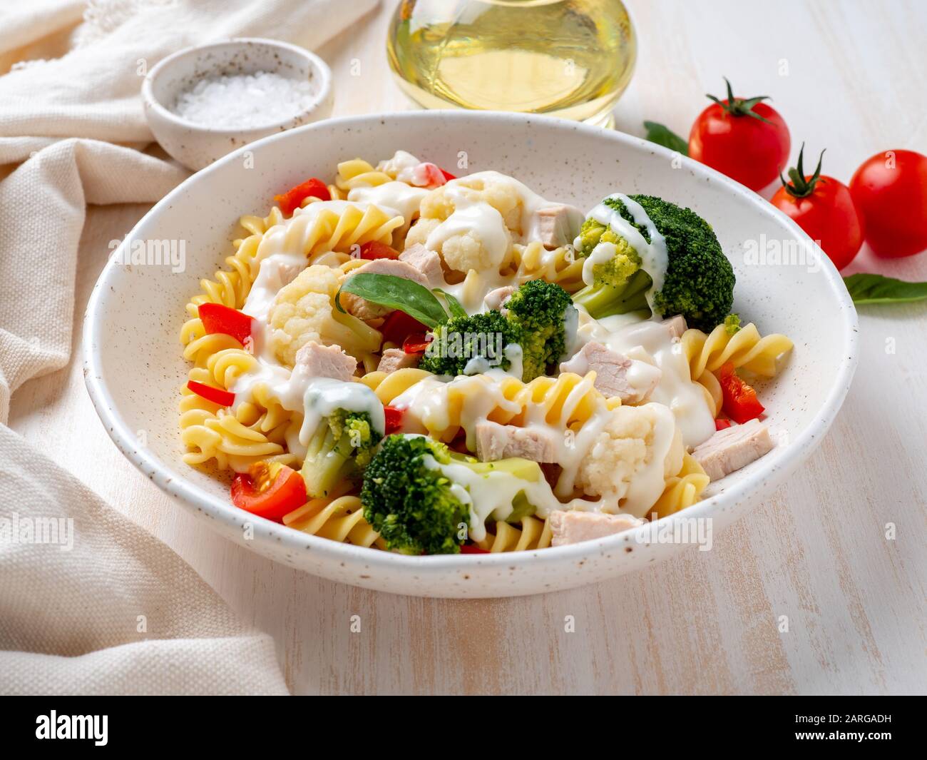Nudelfusilli mit Gemüse, gekochtem gedämmtem Fleisch, weißer Soße auf weißem Holztisch, kalorienarme Ernährung, fettarme Ernährung, Seitenansicht Stockfoto