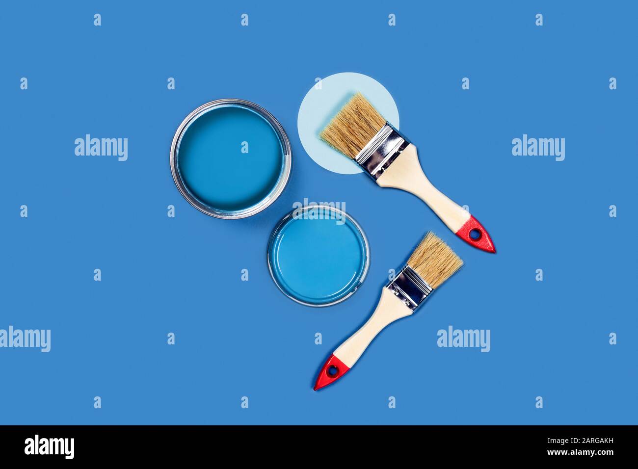 Foto für Wohnungsreparaturen. Blauer Hintergrund mit zwei lackierten Holzquasten und einer Kreis- und Lackkelle. Flaches Layout, Draufsicht, Kopierbereich. Stockfoto