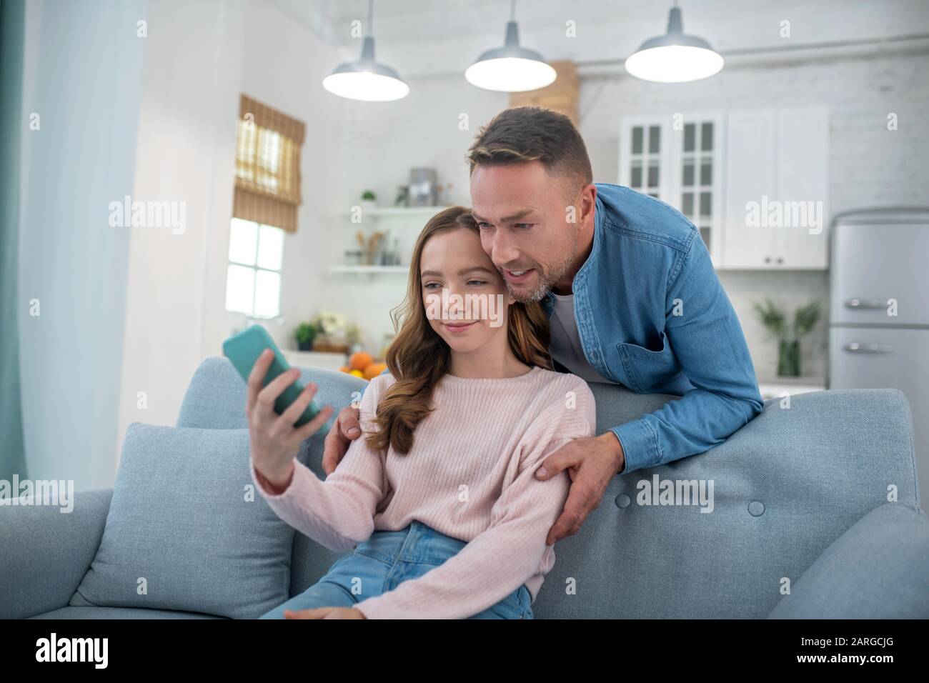 Papa mit Tochter sieht sich den Smartphone-Bildschirm zufrieden an. Stockfoto