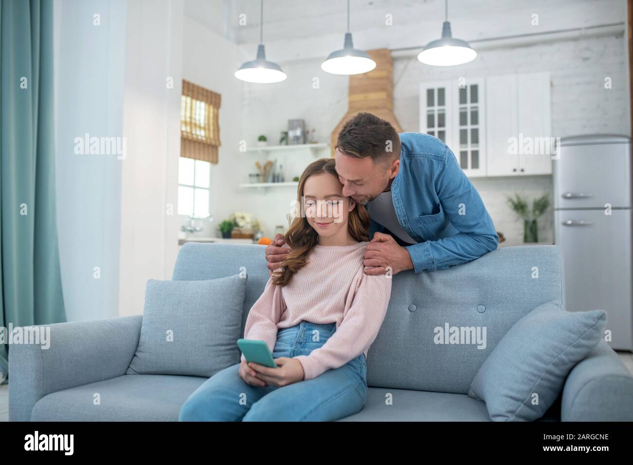 Vater und Tochter sehen sich den Bildschirm eines Smartphones an. Stockfoto