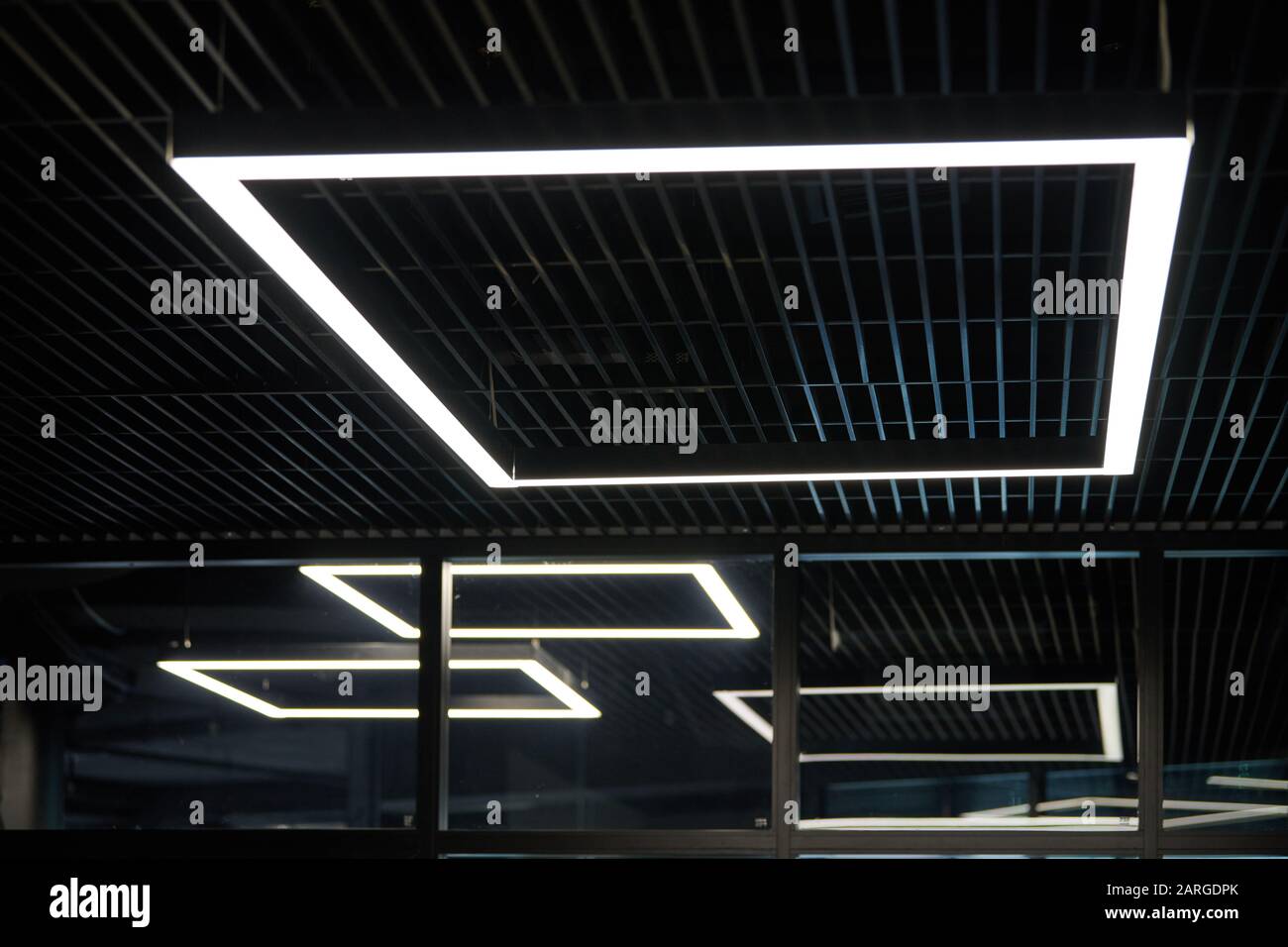 Moderne Bürobeleuchtung. Dünne Lampen in Office dunklen Decke. LED Weiß kaltes Licht über Arbeitsplätze. Stockfoto