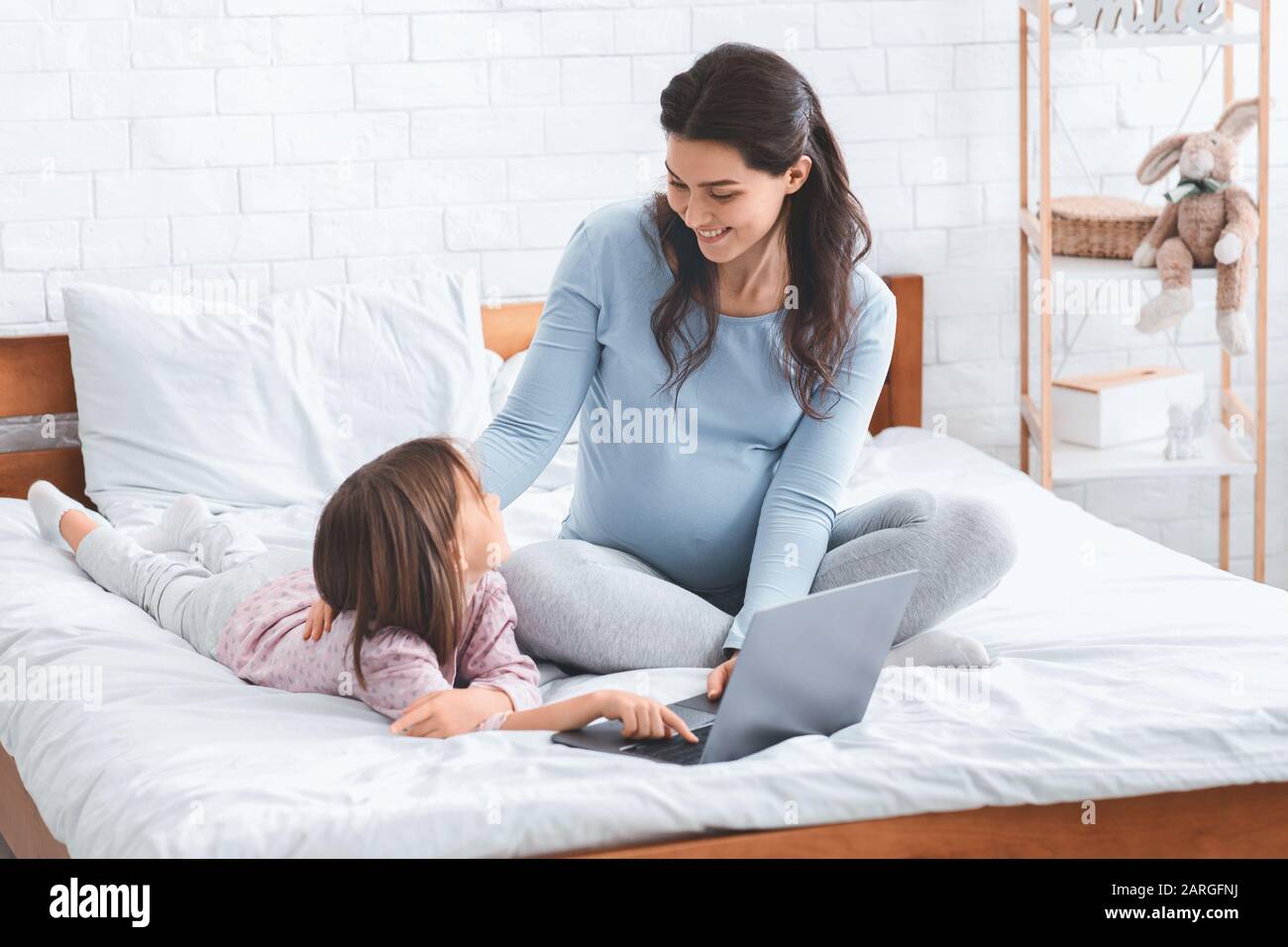 Ich rechne mit Dame und kleinen Mädchen, die ein Wochenende planen, und verwende einen Laptop Stockfoto