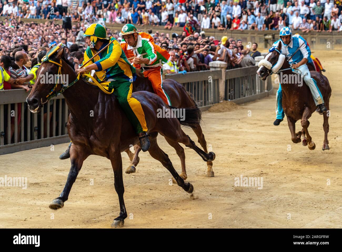 Jockeys in farbenfrohen Outfits, die ihre jeweiligen Wohnviertel (Contrade) repräsentieren und sich für die Führung im Palio, Siena, Toskana, Italien, Europa vieren Stockfoto