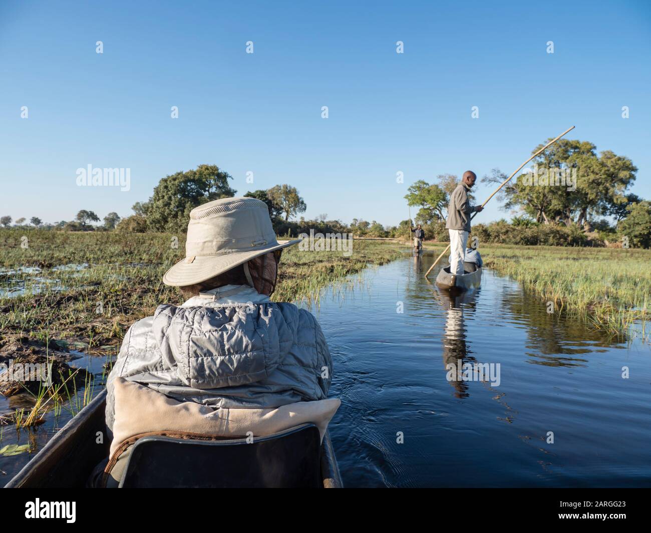 Touristen, die durch das flache Wasser von Mokoro im Okavango-Delta, Botswana, Afrika poliert werden Stockfoto