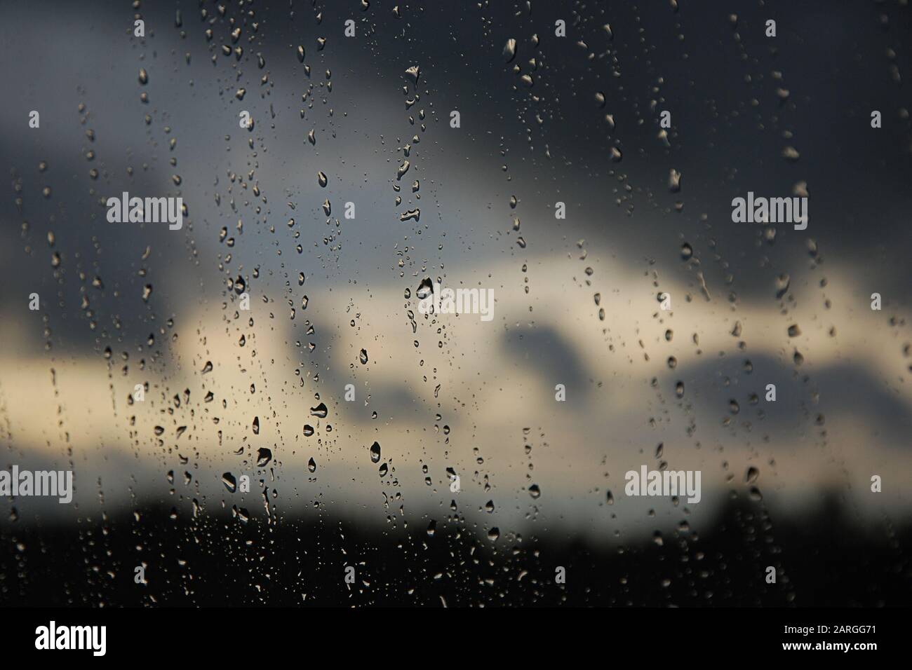 Regentropfen im Fensterbereich. Schwarzer, grauer, weißer Farbverlauf auf unscharfem Hintergrund. Bewölktes Regenwetter außerhalb des Fensters. Kühlung, Regen, schlechtes Wetter Stockfoto