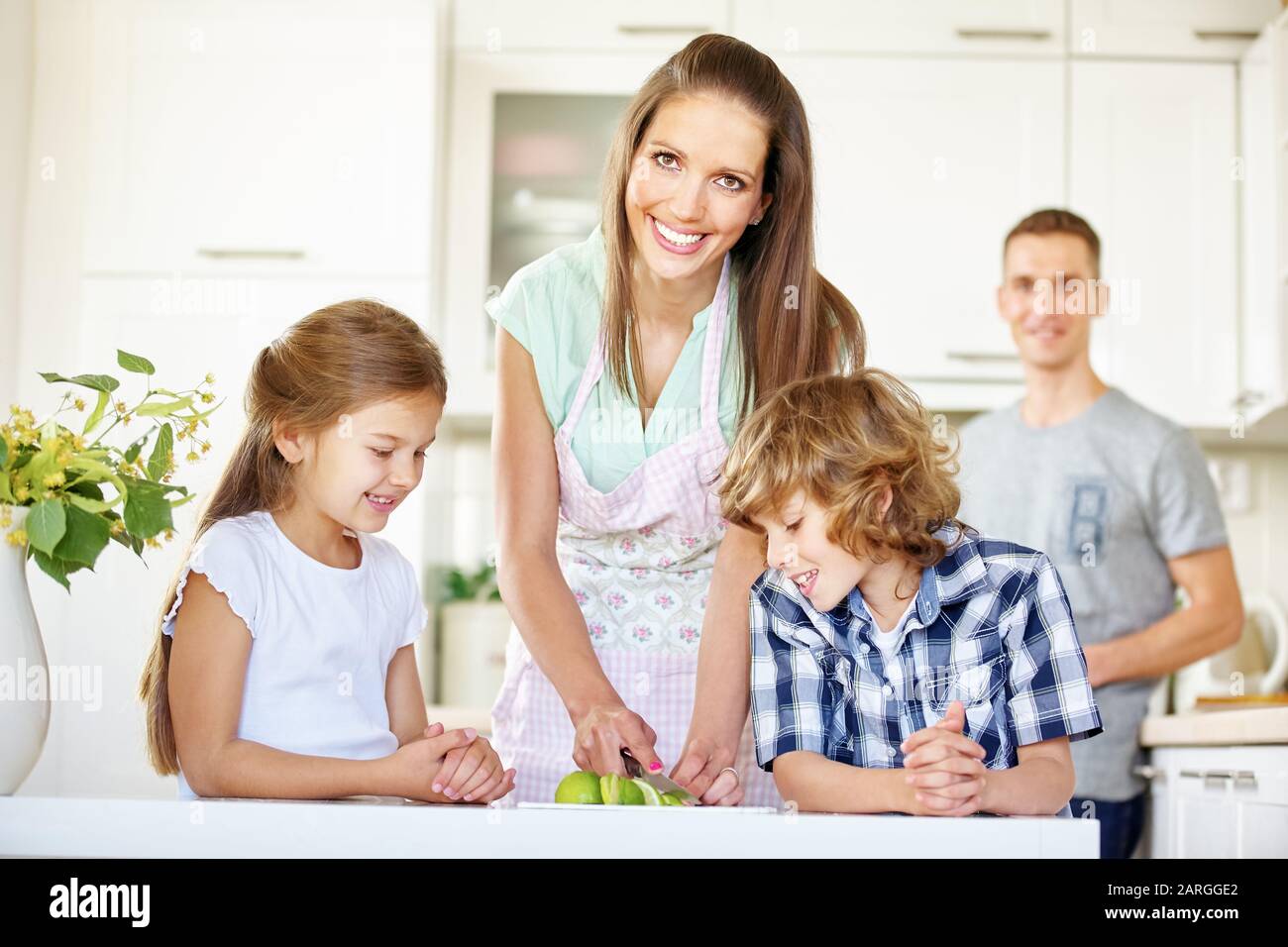 Glückliche Familie mit zwei Kindern schneidet in der Küche Obst Stockfoto