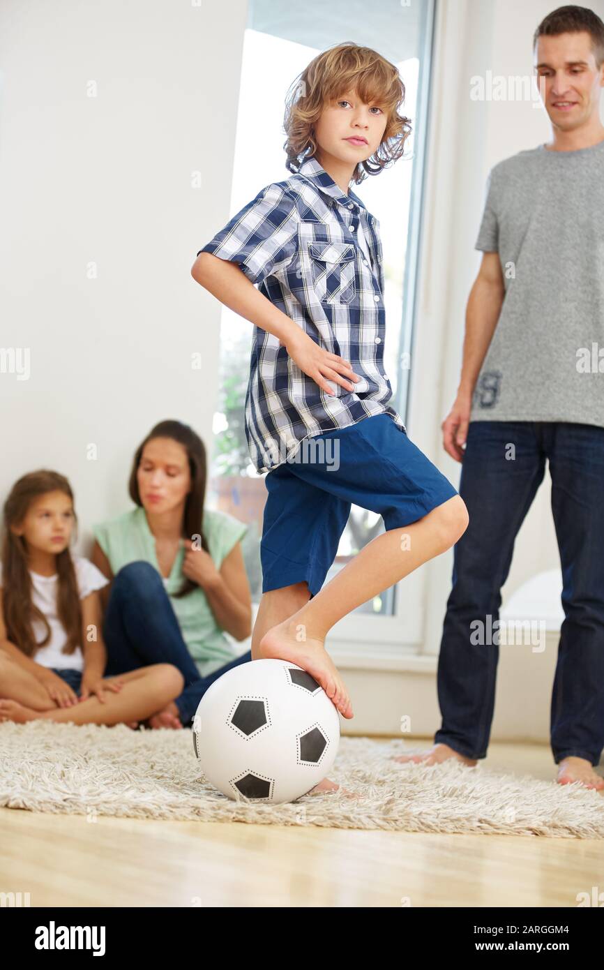 Familie spielt mit Fußball und zwei Kindern im Wohnzimmer Stockfoto