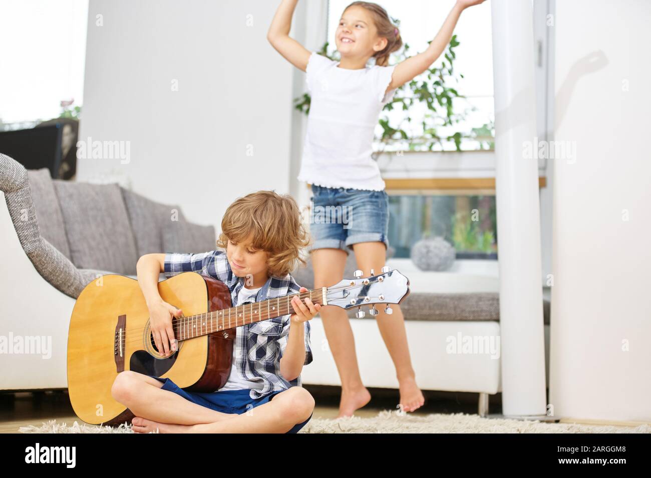 Boy spielt Musik auf Gitarre und Mädchentänze Stockfoto
