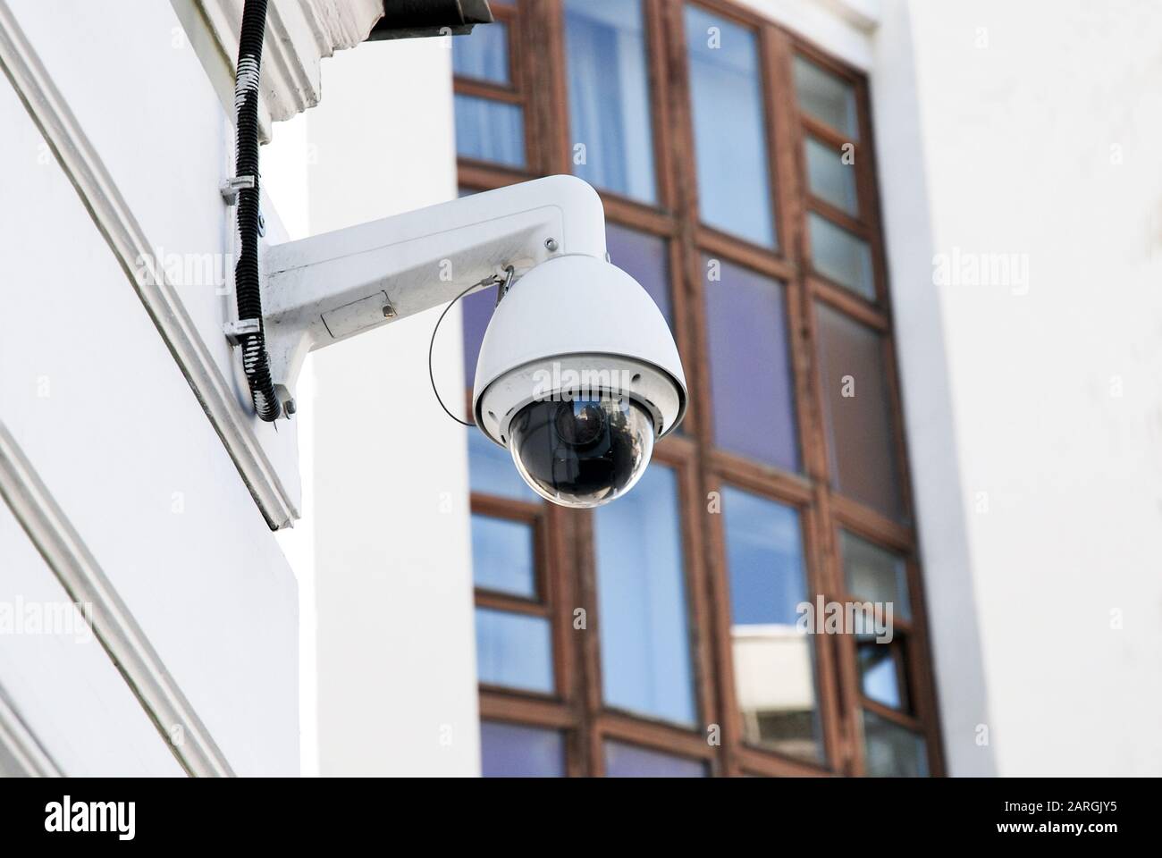 Weiße und schwarze, kugelförmige externe Überwachungskamera an der Gebäudefassade Stockfoto