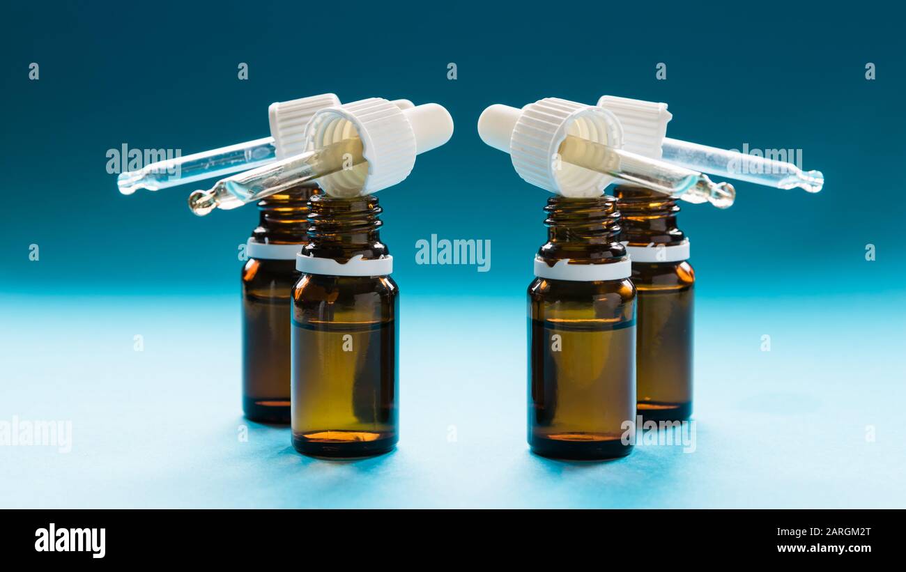 Kosmetologie, Glasflaschen mit Pipetten und Kosmetik auf blauem Hintergrund Stockfoto