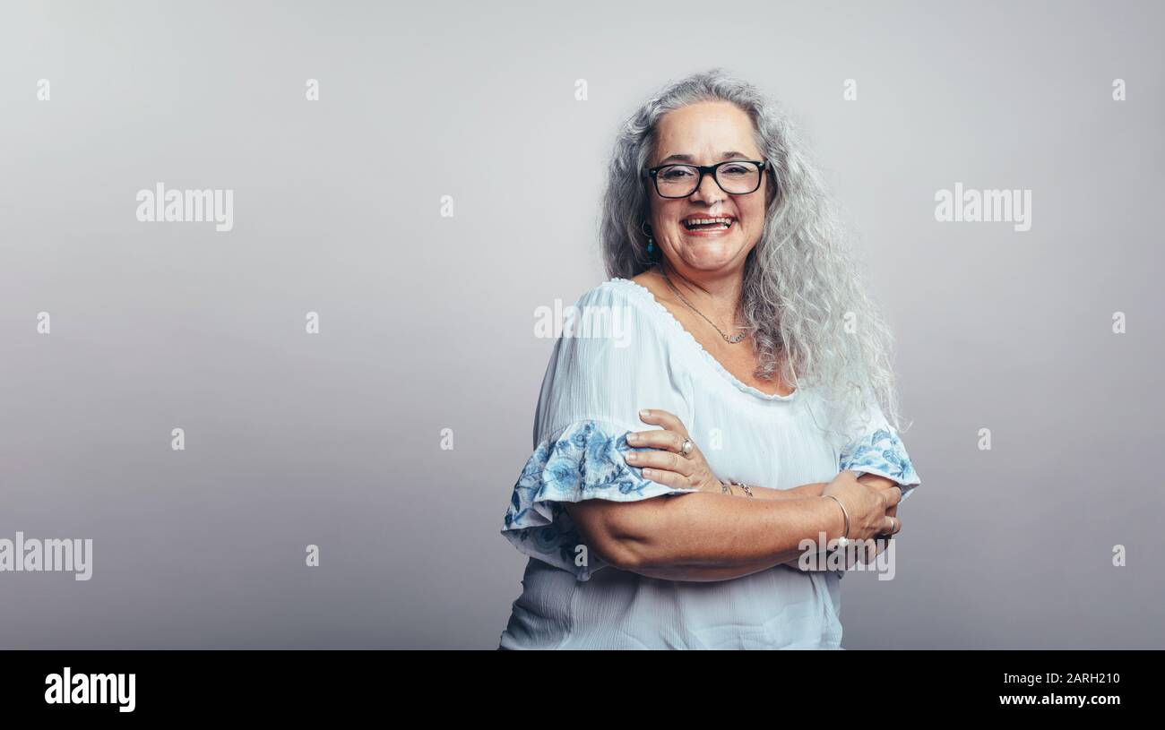 Lächelnde alte Frau in weißen Haaren isoliert auf grauem Hintergrund. Glückliche Seniorin in Brillen mit Blick auf die Kamera. Stockfoto