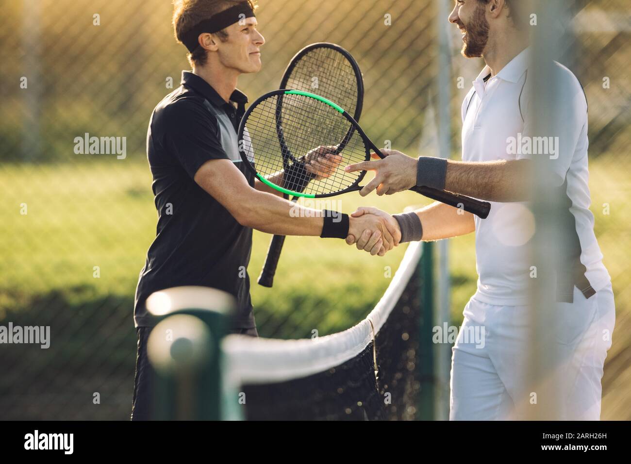 Professionelle Tennisspieler schütteln die Hände im Netz. Zwei Sportler schütteln nach dem Spiel die Hände über das Netz. Stockfoto