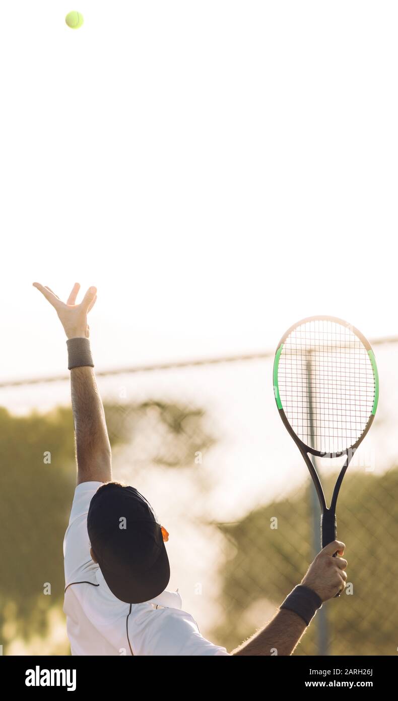 Junger Mann wirft einen Tennisball zum Aufschlag. Tennisspieler, der den Ball in einem Spiel serviert. Stockfoto