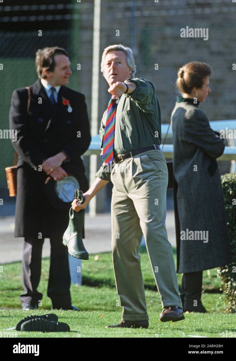 Michael Aspel tritt im November 1990 in einem "Welie Fling" auf der Sandown Park Racecourse in England an Stockfoto