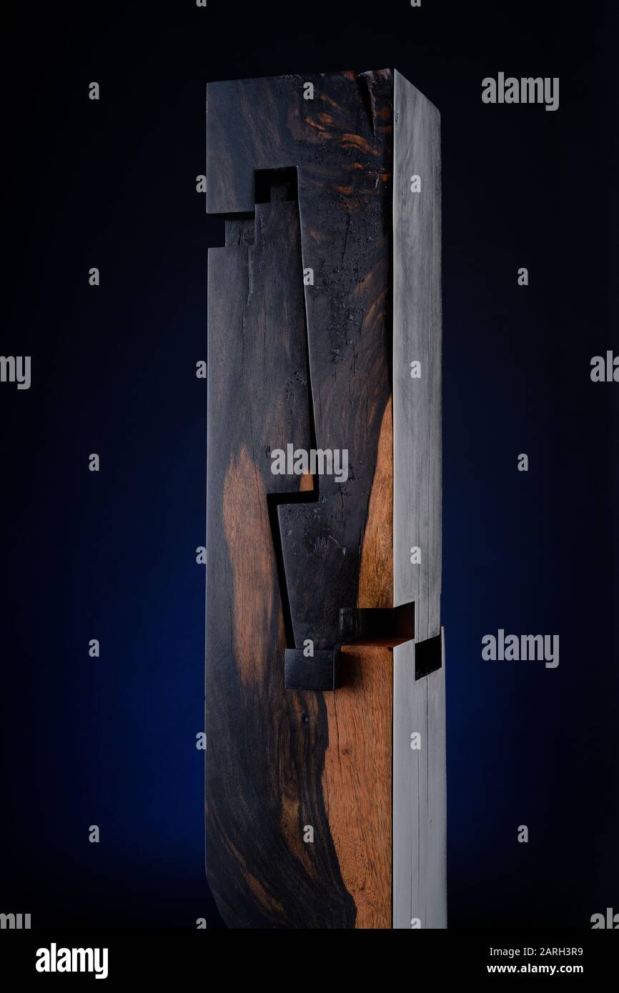 Holzskulptur von Abdollah Nafisi. Verebnete Holzschnitte in Abschnitten. Saß auf einer schwarzen Sockelplatte mit einem blauen Leuchten dahinter. Stockfoto
