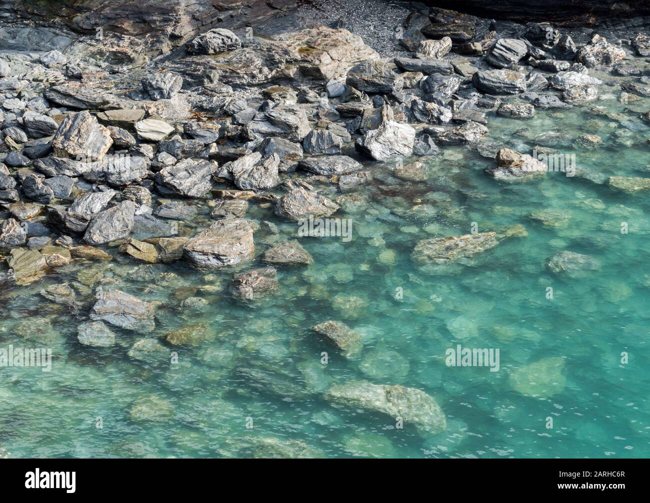 Kristallklares türkisfarbenes Wasser über Felsen am Strand, Cornwall, Großbritannien Stockfoto