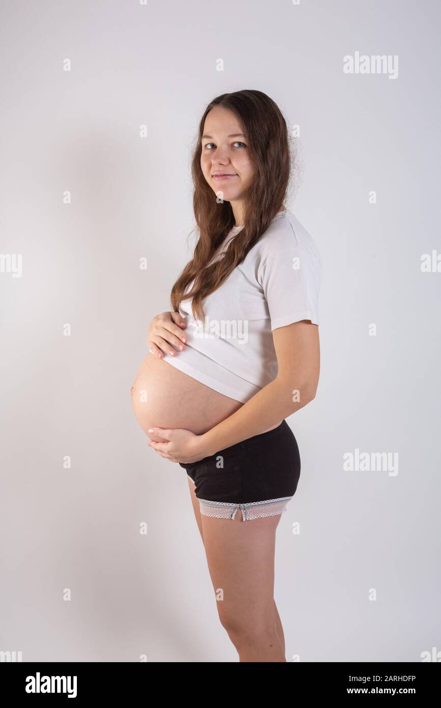 Die junge schöne schwangere Frau erlebt starke Emotionen auf weißem Hintergrund Stockfoto