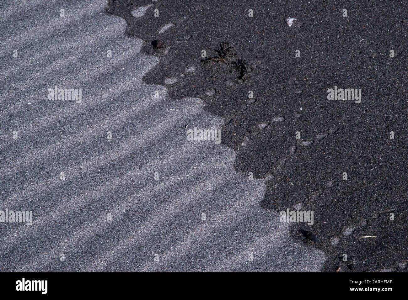 Detail des Wassers, das über schwarzen Sand am Oakura Beach, Neuseeland fließt Stockfoto